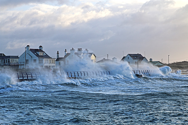 A large wave crashing into homes and causing flooding.