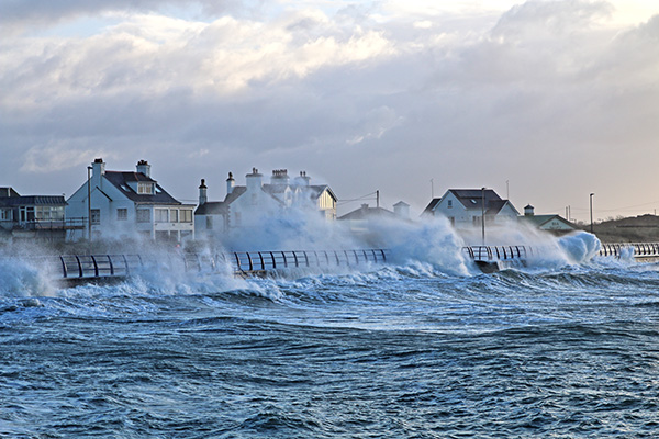 Fundraiser-sec-1. A large wave crashing into homes and causing flooding.